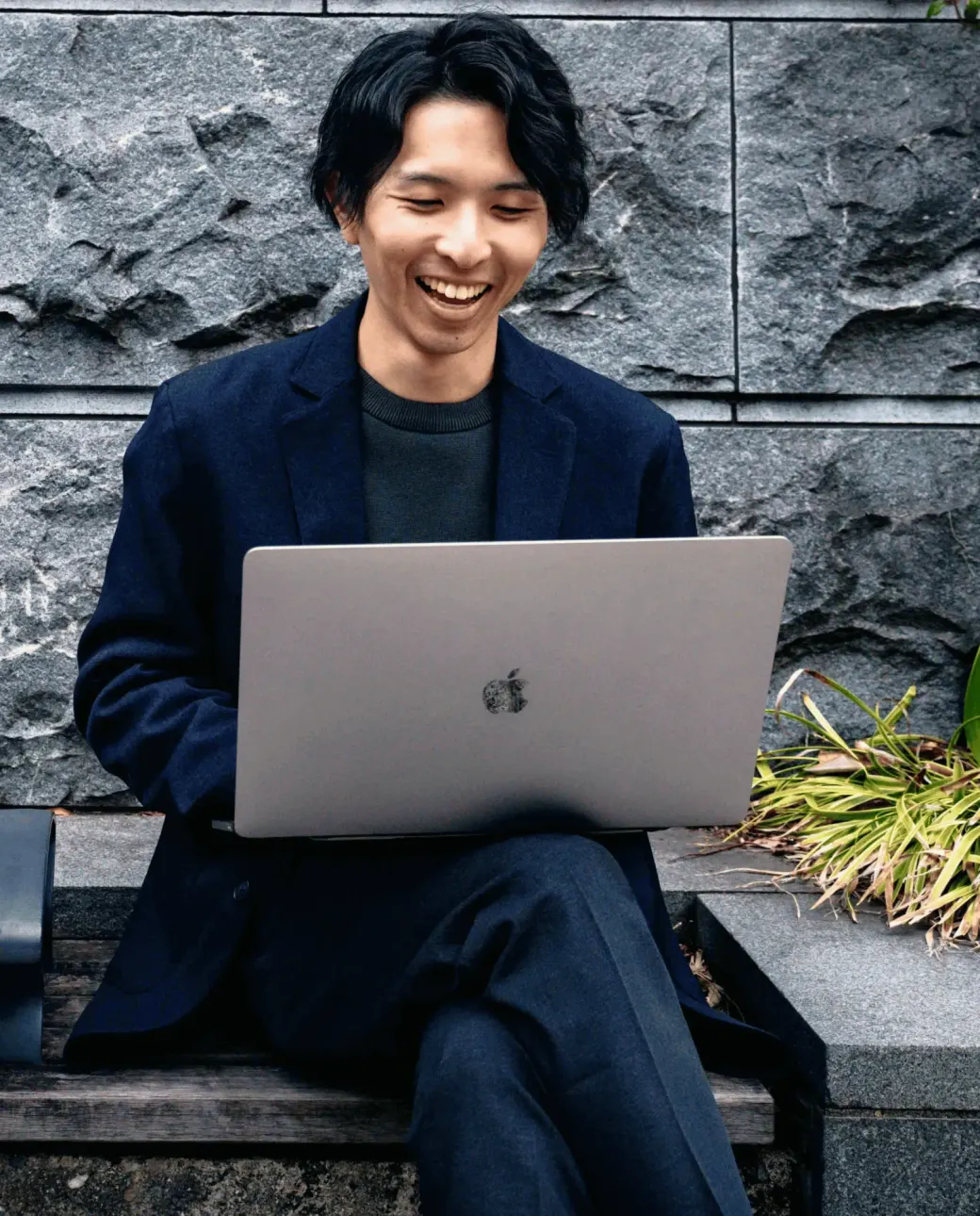 ノートパソコンを開いて笑顔で作業する、BlueStudio代表の新谷